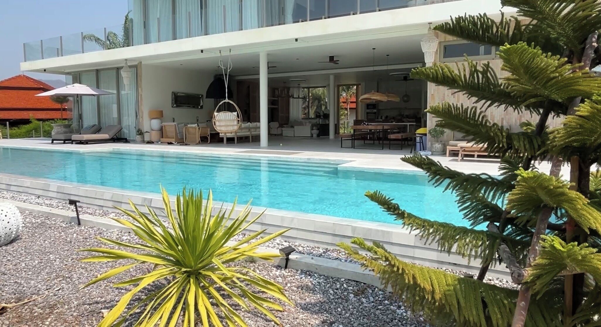 A modern hotel with a swimming pool, outdoor seating, and a covered patio area.
