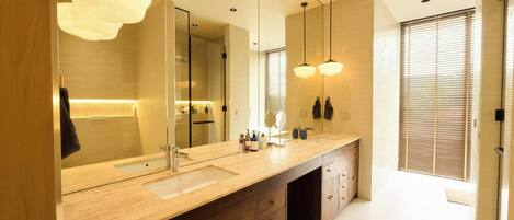 A modern bathroom with a large mirror, dual sinks, and pendant lighting.