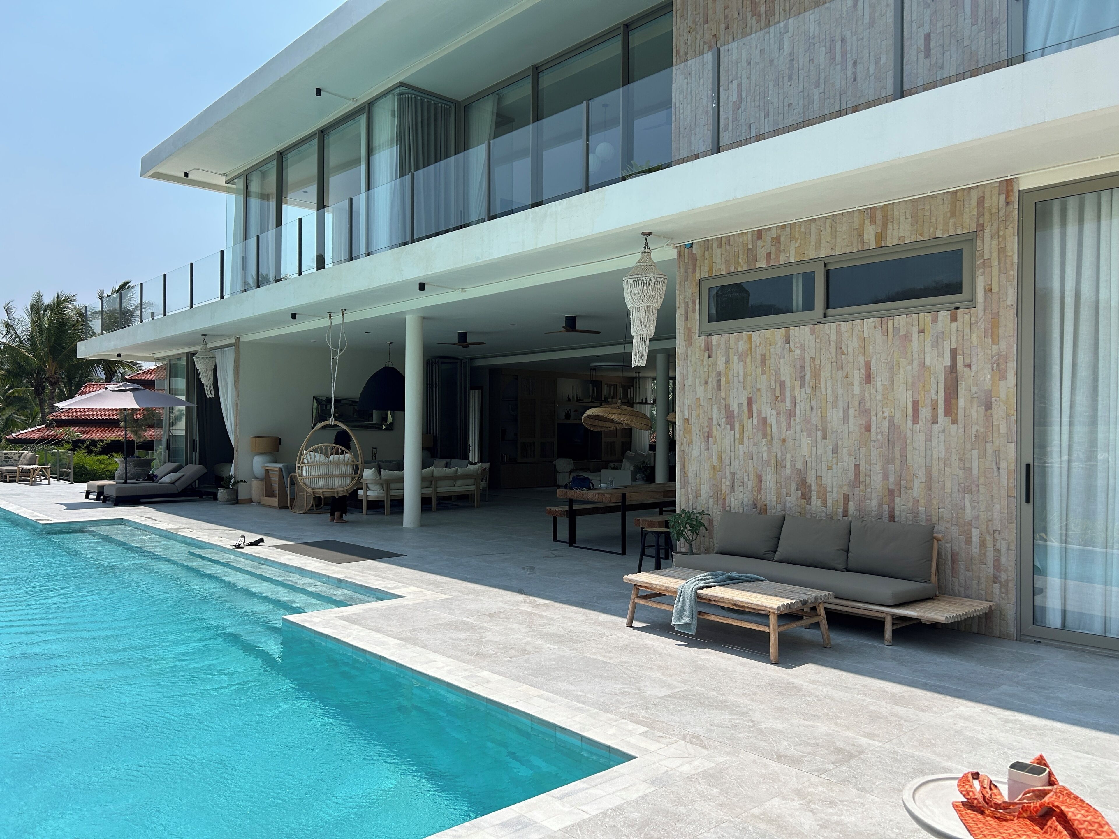 Ein modernes Haus mit Pool, Sitzgelegenheiten im Freien und einem Essbereich.