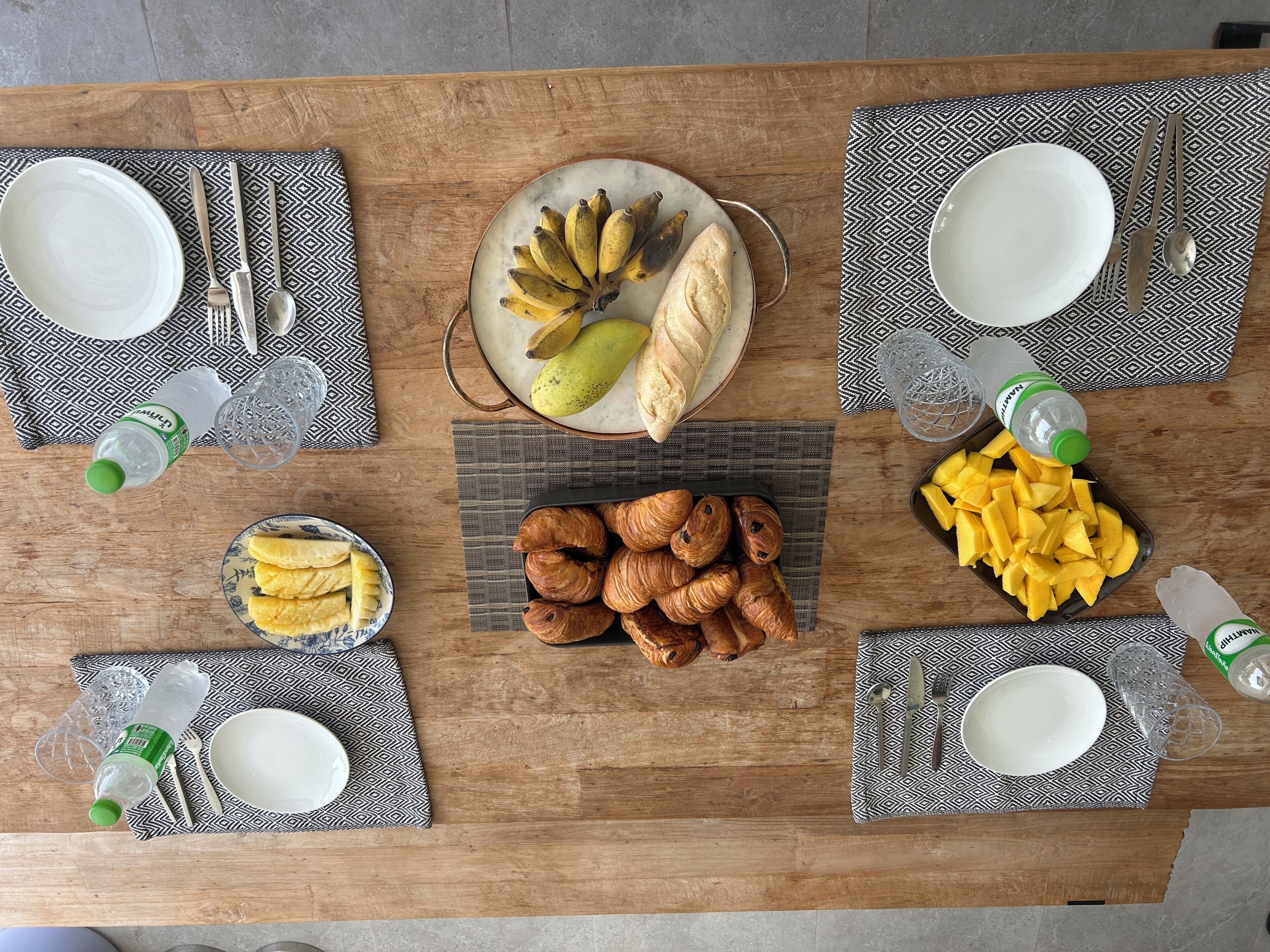 A dining table set with plates, cutlery, and various food items.