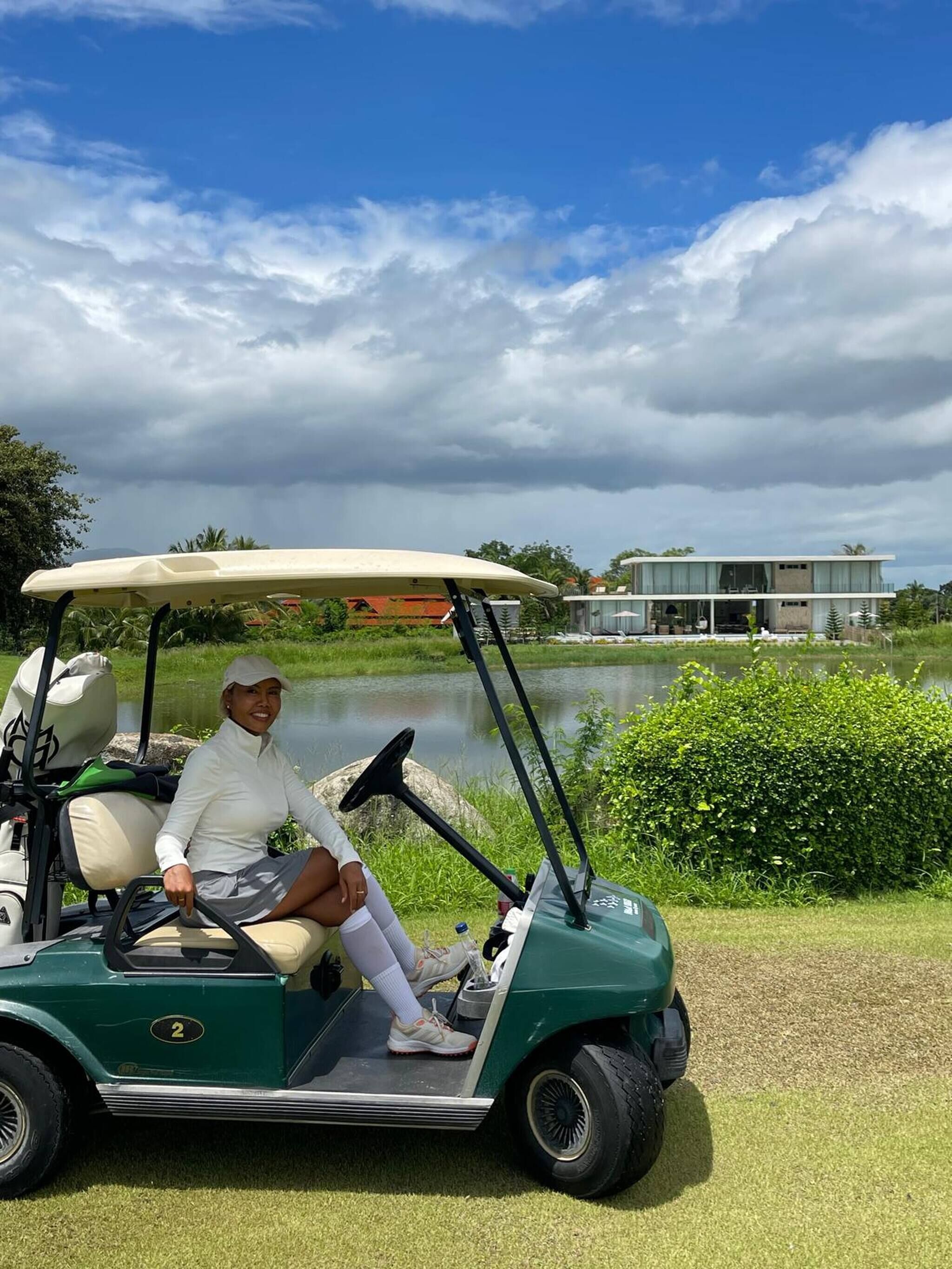A golf cart parked near a body of water with a modern building in the background.