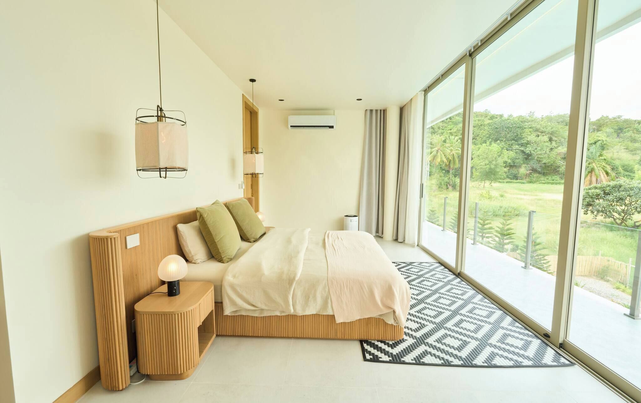 A modern bedroom with a large window, a bed with a headboard, bedside tables, and a view of greenery outside.