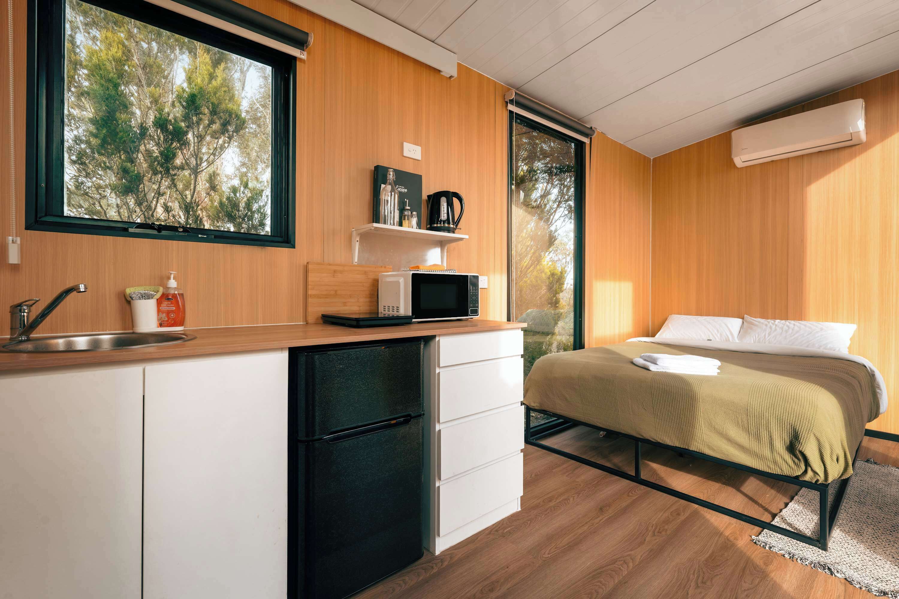 A compact bedroom with a bed, a bedside table, and a window.