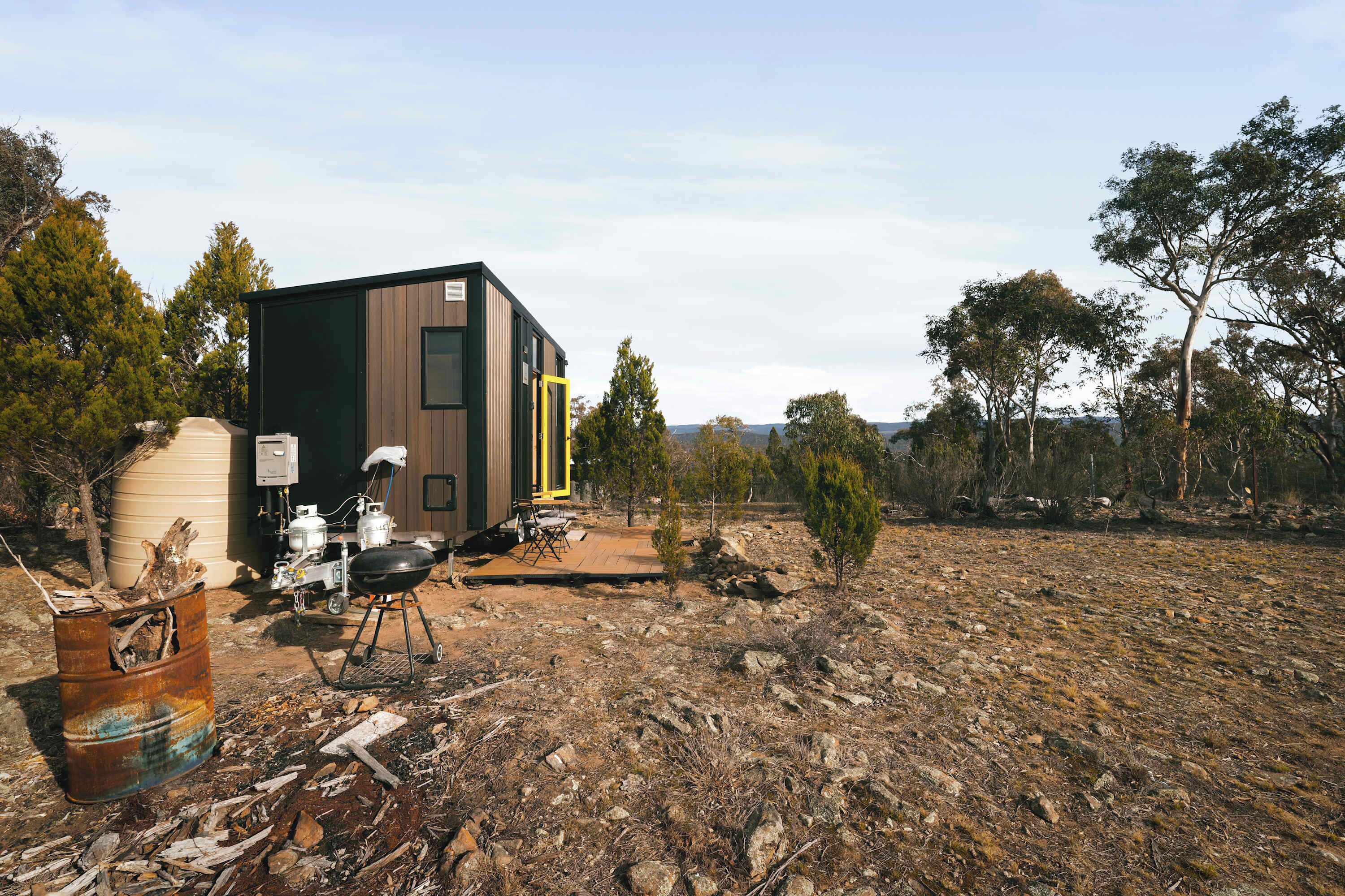 A modern, compact building with a flat roof, situated in a natural, rocky landscape with sparse vegetation.