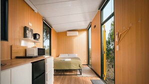 A compact bedroom with a bed, bedside table, and a window.