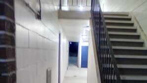 Ein Korridor mit Treppe, weißen Wänden und einer Ziegelwand an einer Seite.