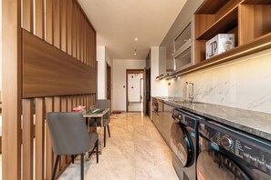 Eine moderne Küche mit Waschmaschine, einer Essecke mit Tisch und Stühlen sowie Holzvertäfelung an einer Wand.