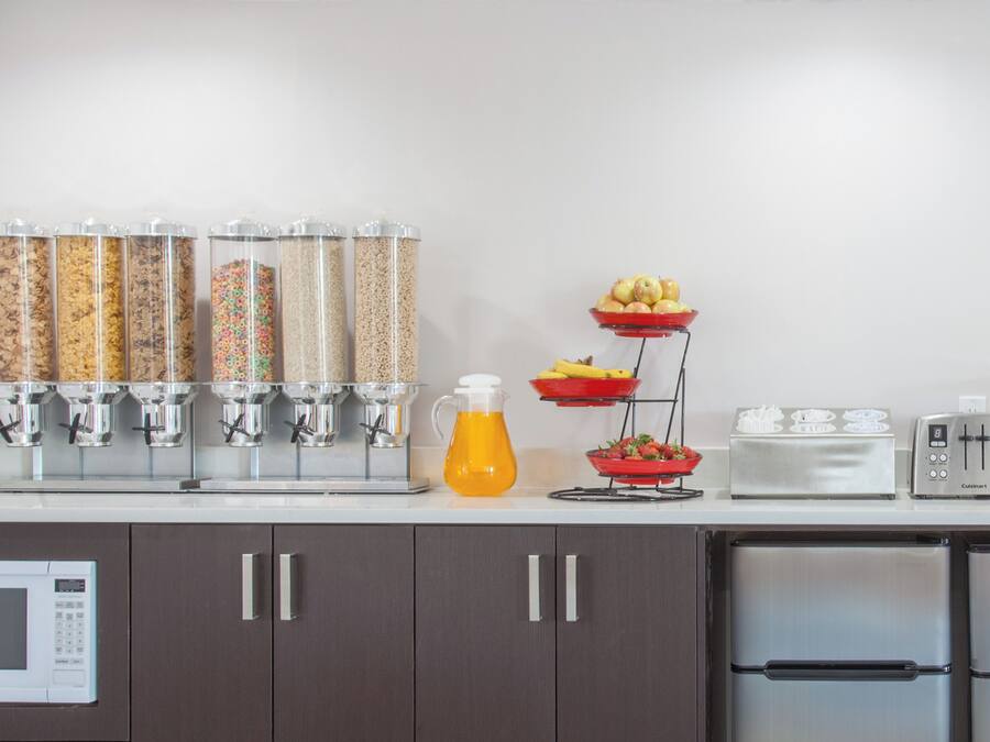 A kitchen with a microwave, cabinets, a toaster, and a fruit display.