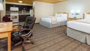 A hotel room with a bed, a desk, a chair, a microwave, and a small kitchenette. - TC Motel (Medicine Hat)