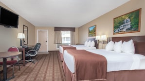 A hotel room with a bed, a desk, a chair, a TV, and a painting on the wall. - TC Motel (Medicine Hat)