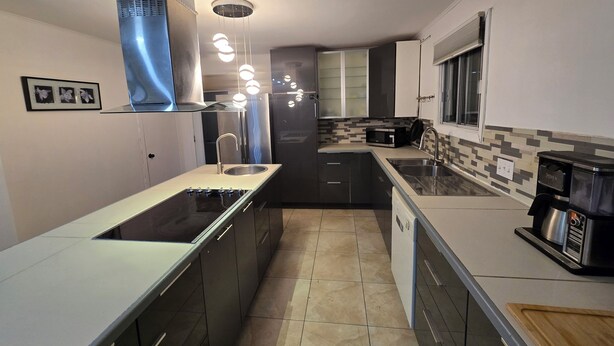 A modern kitchen with a central island, stainless steel appliances, and a tiled backsplash. - brossard home inn 1 (Brossard)