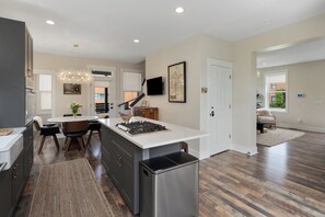 A modern kitchen with a central island, dark wood flooring, and a stainless steel refrigerator. - The Stella: The Star of the Short North! (Columbus)