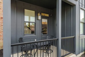 A gray building exterior with a balcony, a door, and a window. - The Stella: The Star of the Short North! (Columbus)