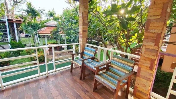 A balcony with wooden furniture and a view of a garden. - Nada Koh Larn Resort (Koh Lan)