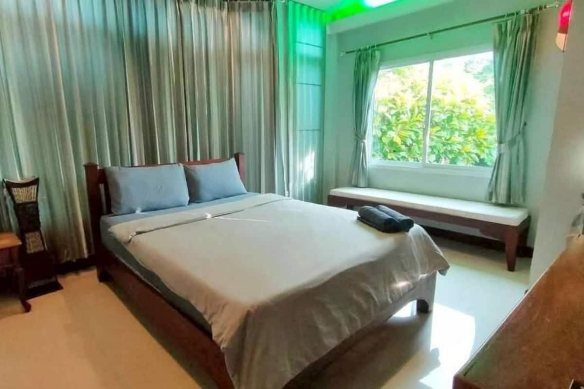Un dormitorio con cama, una banca, una mesita de noche y una ventana con cortinas.