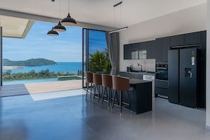 Una cocina moderna con vista al océano, una zona de bar y un amplio ventanal.