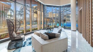 Eine großzügige Lobby mit großen Fenstern, einem modernen Sofa, einem Sessel und einem kleinen Tisch.