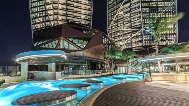 Ein modernes Hotel mit Poolbereich, großen Glasfenstern und einem markanten architektonischen Design.