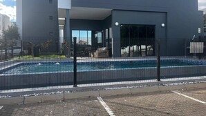 A modern building with a swimming pool, a covered patio, and a view of the surrounding area. - Stylish 1BR Midrand Pool, Wifi & Secure Parking (Johannesburg)