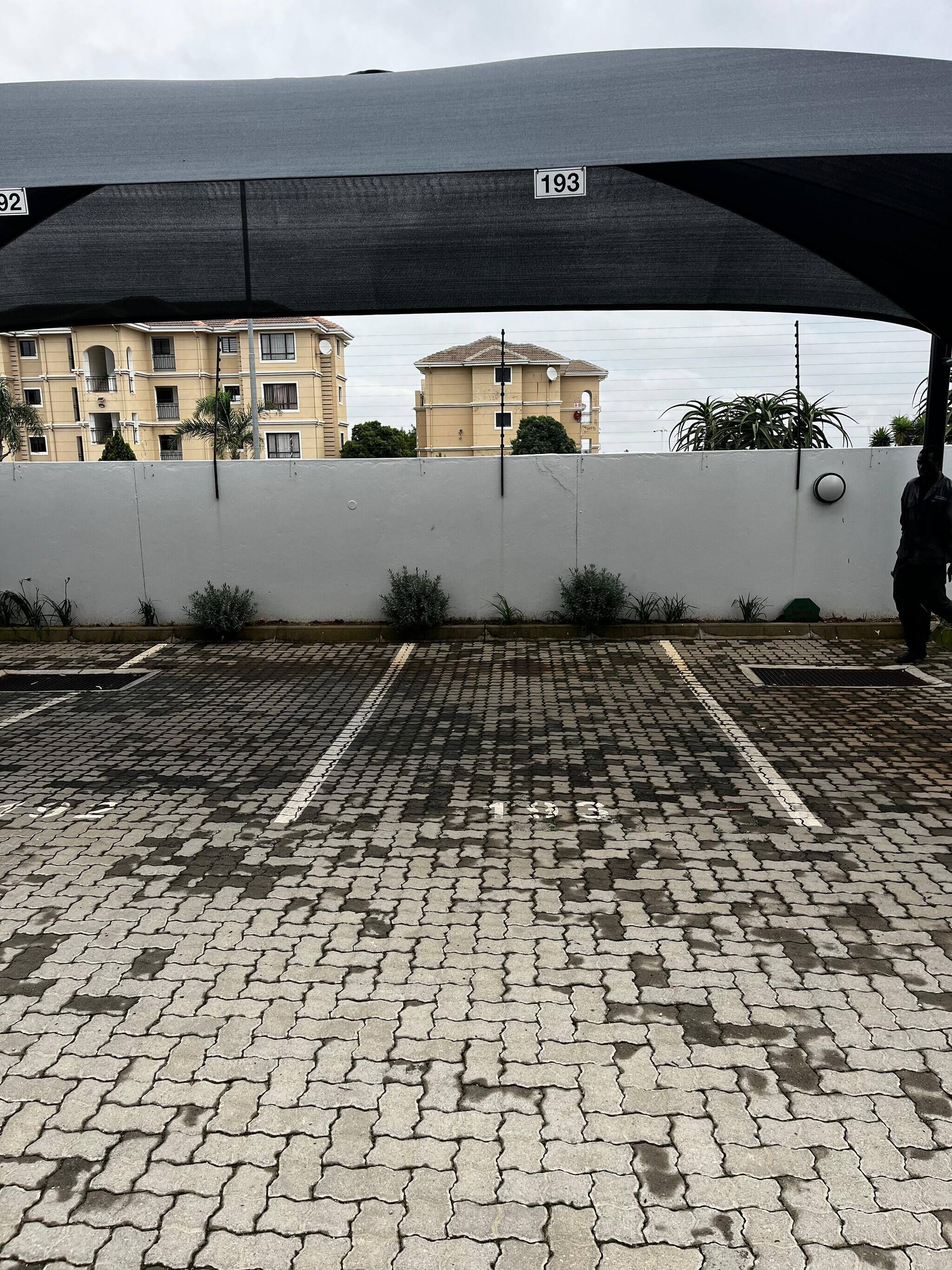A parking area with a white wall and a black canopy.