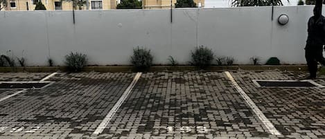 A parking area with a white wall and a black canopy.