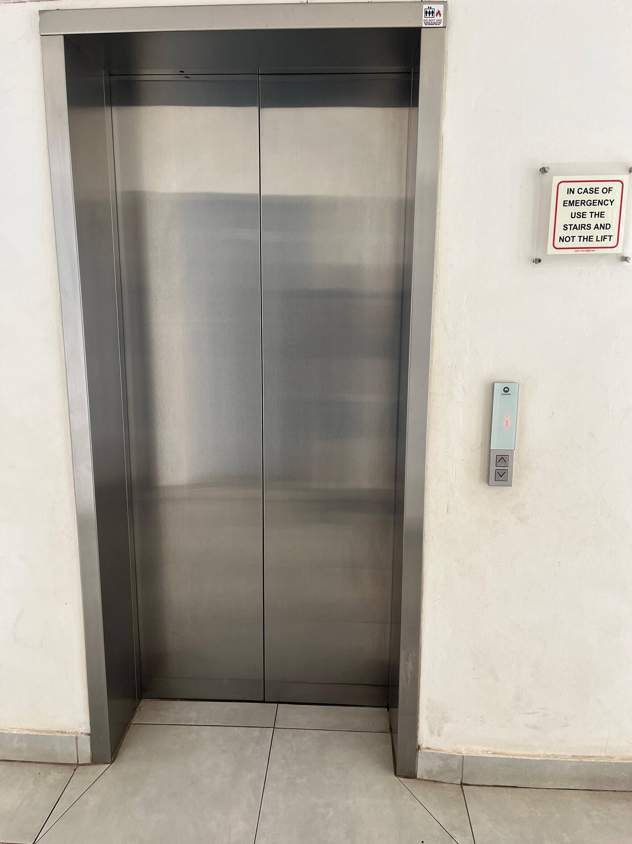 Une porte d’ascenseur fermée, avec un panneau indiquant qu’il faut utiliser les escaliers en cas d’urgence.