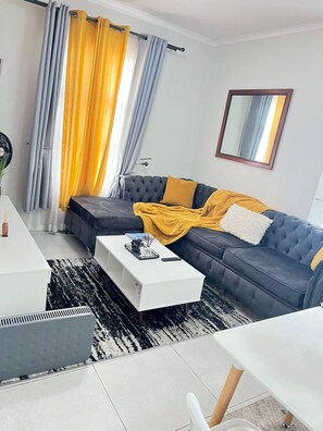 Ein modernes Wohnzimmer mit Sofa, Couchtisch und Essbereich.