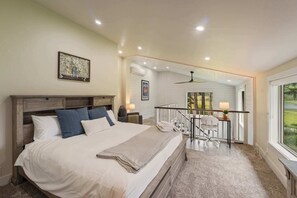 Un dormitorio con una cama grande, un balcón con barandilla y vistas al exterior.