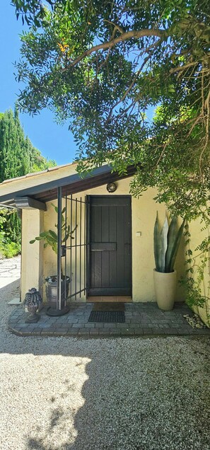 A building with a black door, a covered entrance, and a potted plant. - Provençal villa facing the Gulf of Saint-Tropez (roquebrune)