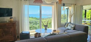 A living room with a sofa, a small round table, and a TV on a wooden cabinet. - Provençal villa facing the Gulf of Saint-Tropez (roquebrune)