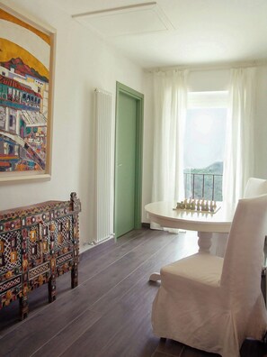 Una stanza con una scacchiera, una porta verde, una sedia bianca e un quadro appeso al muro.
