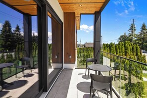 Un balcon dotĂ© de rampes en verre, dâun plafond en bois et dâun espace salon extĂ©rieur.