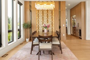 A dining area with a wooden table, chairs, a chandelier, and a potted plant. - Premium Villa for Family Reunions & Wedding Stays (Surrey)