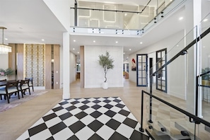 Ein modernes Interieur mit einem Schachbrettfußboden, einer Treppe und einer Essecke mit Tisch und Stühlen.