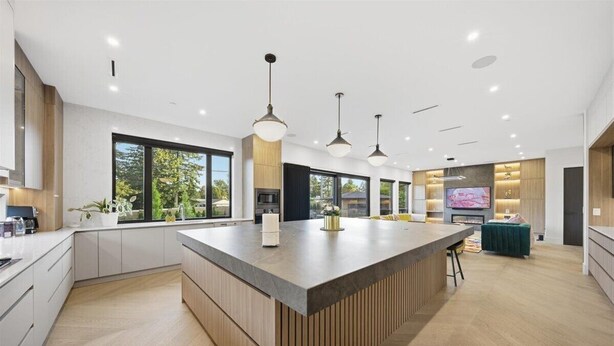 Una cocina moderna con una isla grande, iluminación colgante y amplias ventanas.