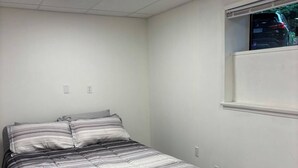 Ein Schlafzimmer mit einem Bett, einem Fenster und einer Deckenleuchte.