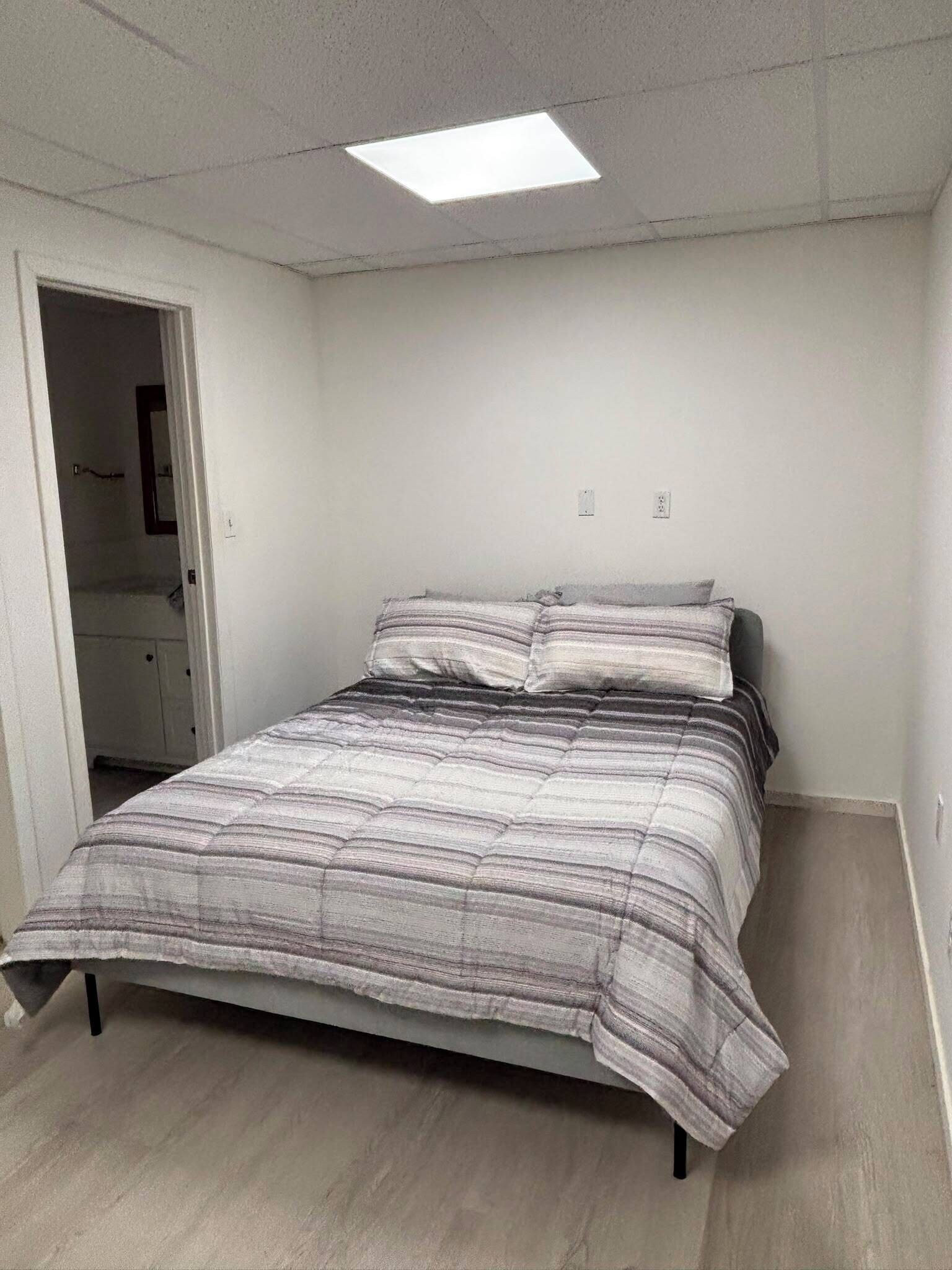 Une chambre à coucher avec un lit, une porte et un luminaire au plafond.