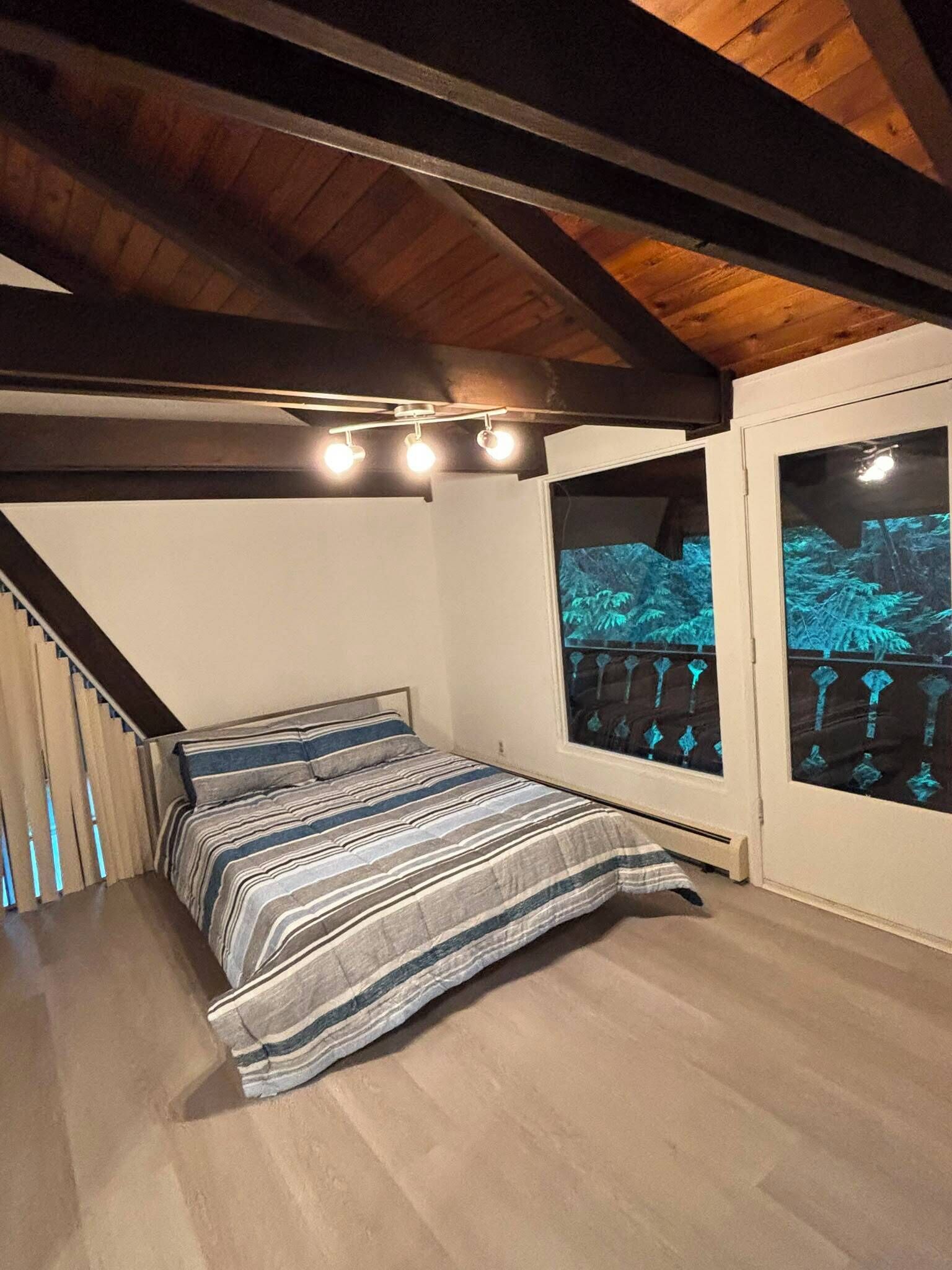 A bedroom with a bed, a window with a view, and a staircase.