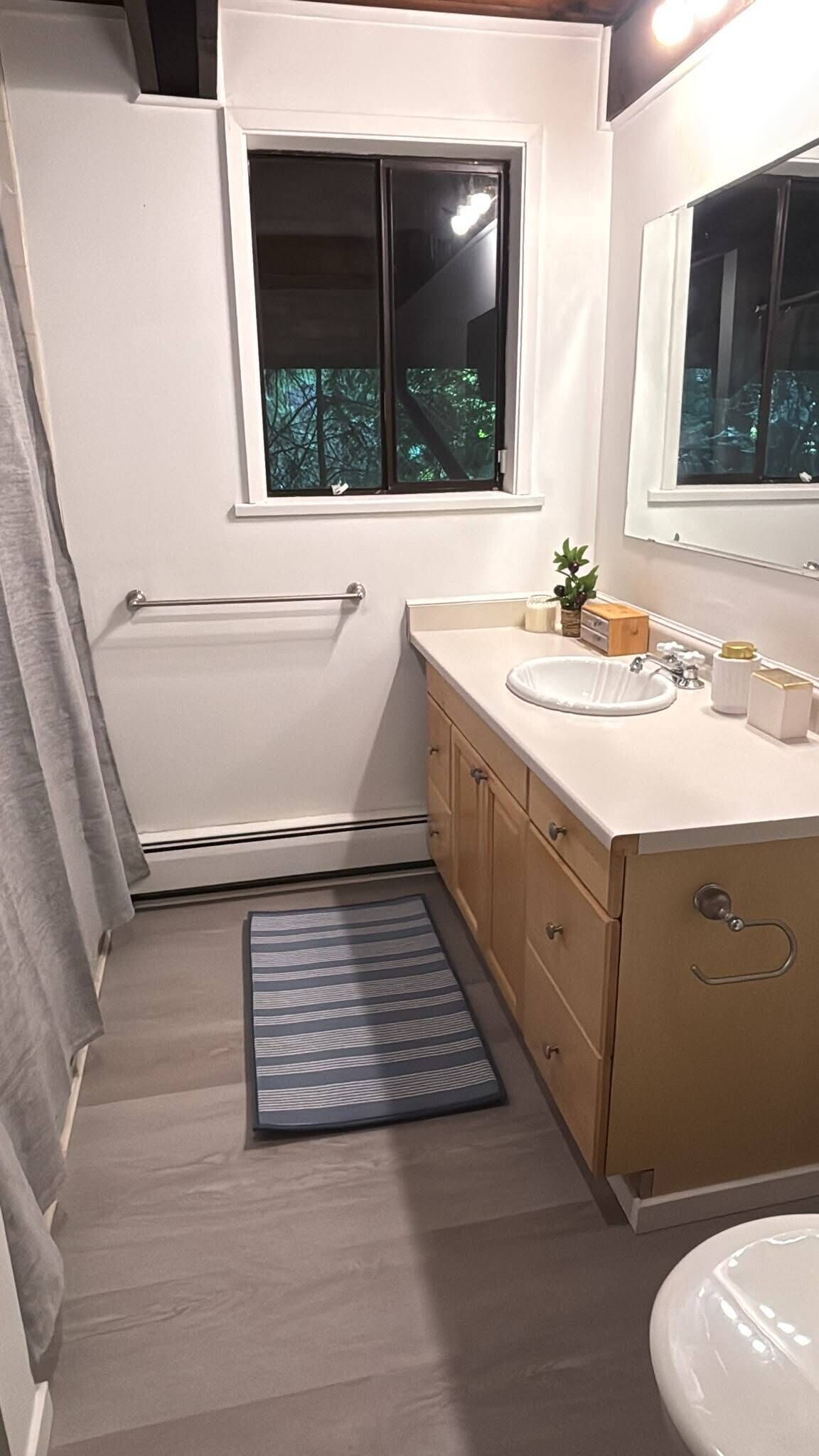 Ein Badezimmer mit Badewanne, Fenster, Waschbecken und Spiegel.