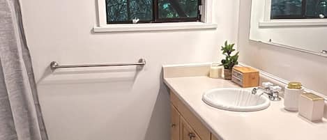 Un bagno con una vasca, una finestra, un lavandino e uno specchio.