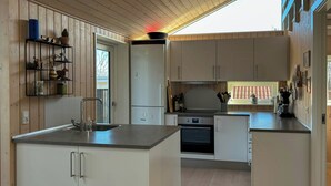 Une cuisine moderne dotée d’un îlot central, d’appareils électroménagers intégrés et de meubles de rangement en bois.