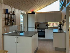 Eine moderne Küche mit einer zentralen Kochinsel, integrierten Geräten und Holzschränken.