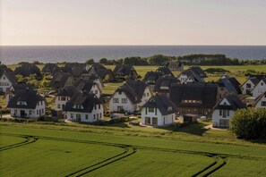 Ein Küstendorf mit traditionellen Häusern, Blick auf das Meer und gepflegten, grünen Feldern.