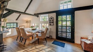 Un coin repas comprenant une table et des chaises, une plante en pot et une fenêtre donnant sur un paysage verdoyant.
