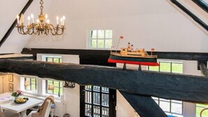 Une pièce avec un lustre, une maquette de bateau et une table ornée de fleurs.