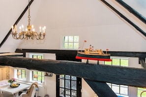 Ein Zimmer mit einer Kandelaber, einem Modellschiff und einem Tisch mit Blumen.