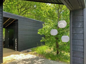 A wooden building with a door and a small outdoor area with a tree and hanging lanterns. - Holiday home with panoramic view of Aarhus Bay (Knebel)
