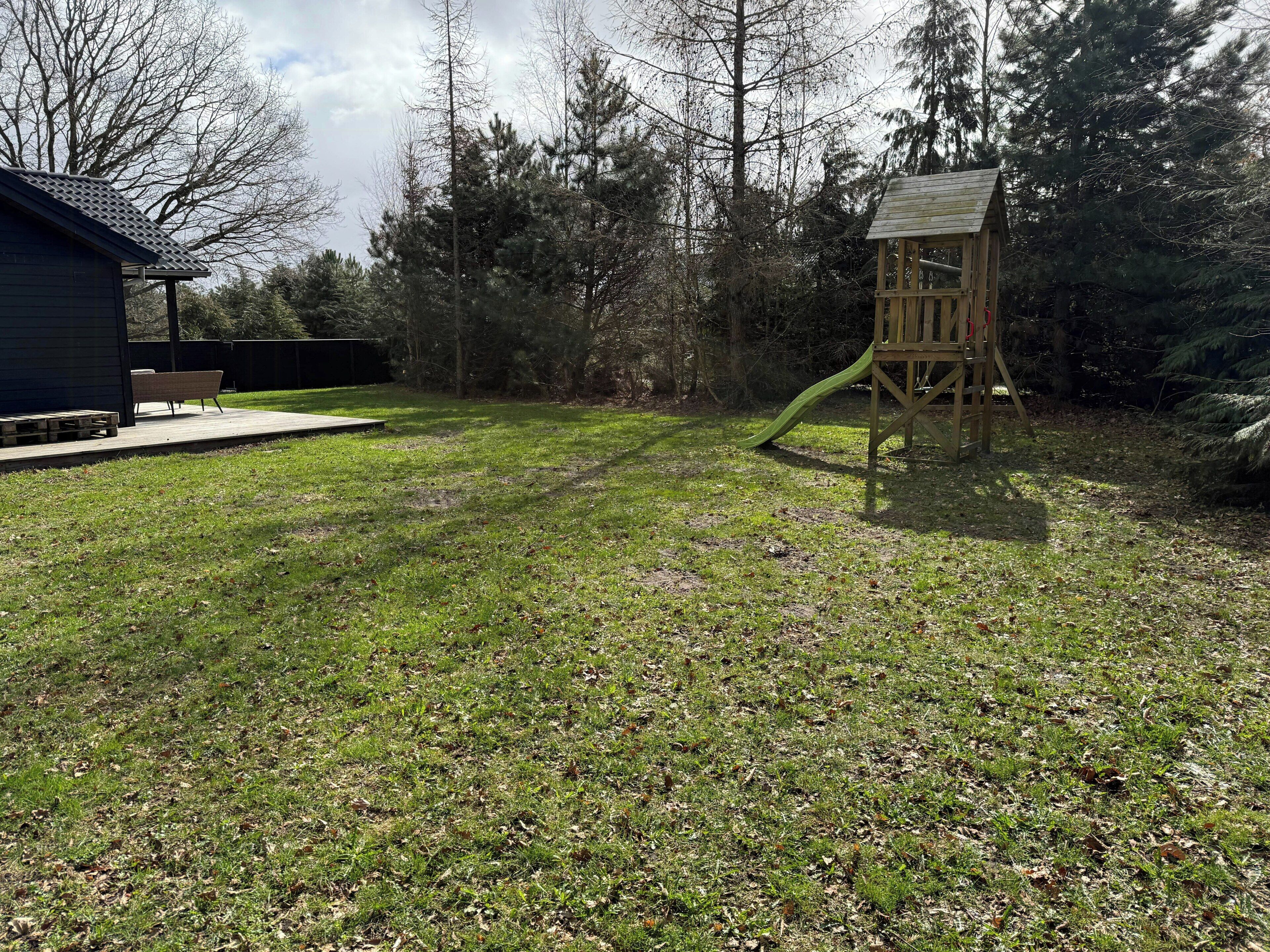 Ein Rasenplatz mit einer hölzernen Spielanlage und einem Schuppen.
