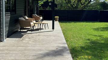 A wooden deck with outdoor furniture, a covered patio, and a grassy yard.