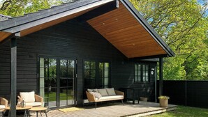 A modern wooden house with a deck, two wicker sofas, and a small table. - Modern wooden house built in a classic style (Glesborg)